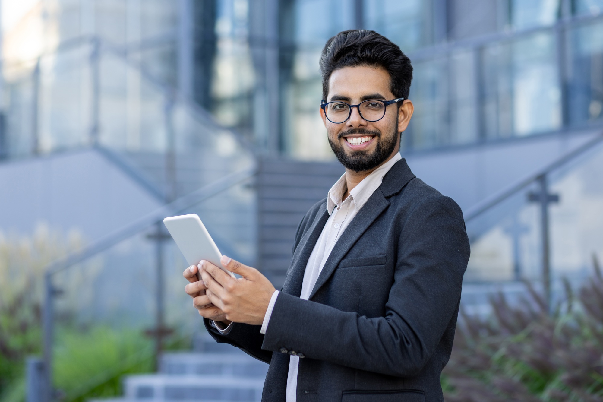 Professional Indian businessman using tablet with a smile outdoors